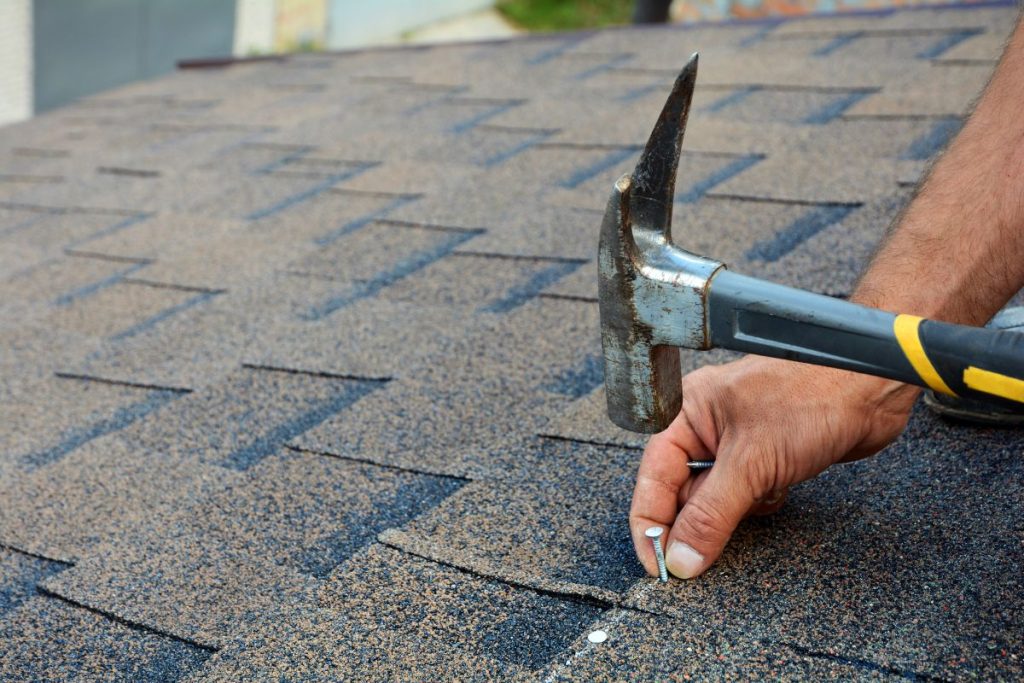 Roof. Roofer is hammering a Nail in the Roof Shingles, St Paul